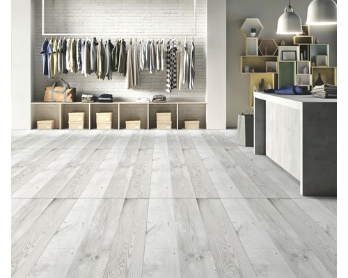 Cameră luminoasă cu podea de lemn, haine pe suport și rafturi