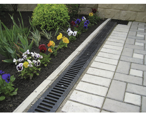 Scenă de grădină cu canal de scurgere între stratul de flori și calea pavată