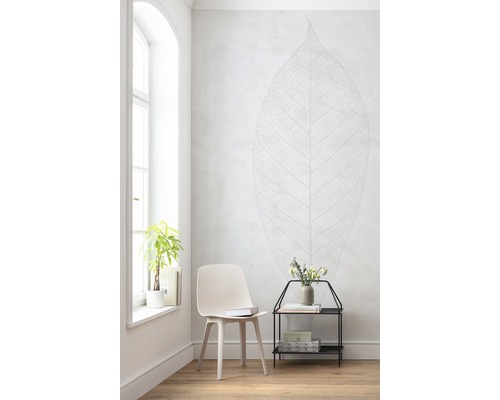 Cameră luminoasă cu scaun, măsuță laterală, plantă și autocolant de perete cu aspect de frunză