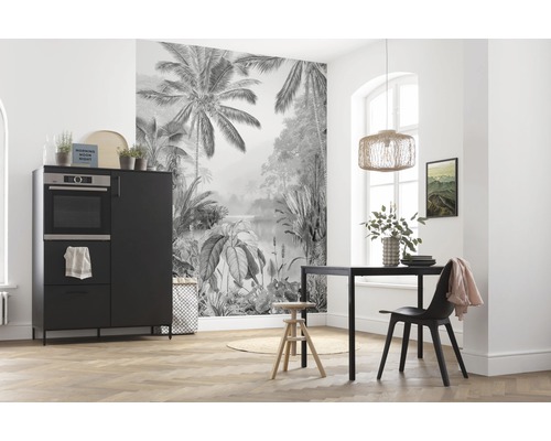 Sufragerie cu masă de sufragerie neagră, scaun și bufet în fața unui fototapet cu motiv de junglă.