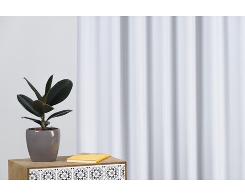 Cameră cu perdea, comodă, carte și plantă de interior