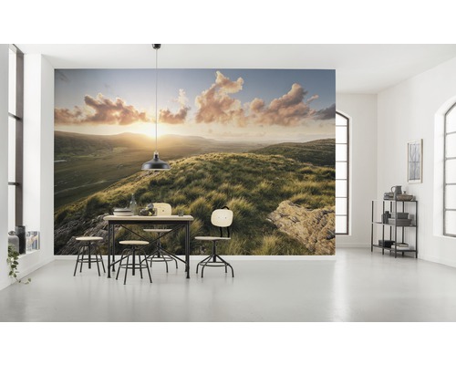 Cameră luminoasă cu fototapet cu un peisaj deluros la răsărit și un set de masă