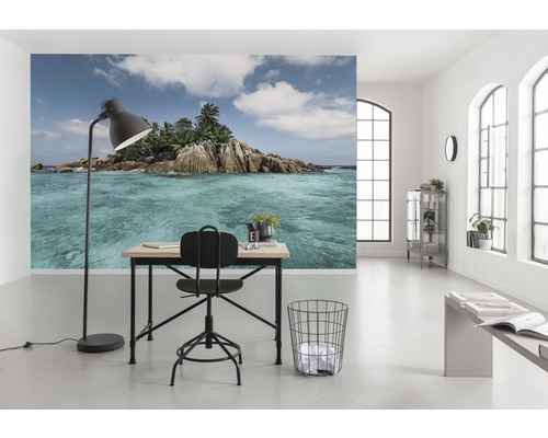 Cameră luminoasă cu un birou, un scaun și un fototapet cu o insulă tropicală