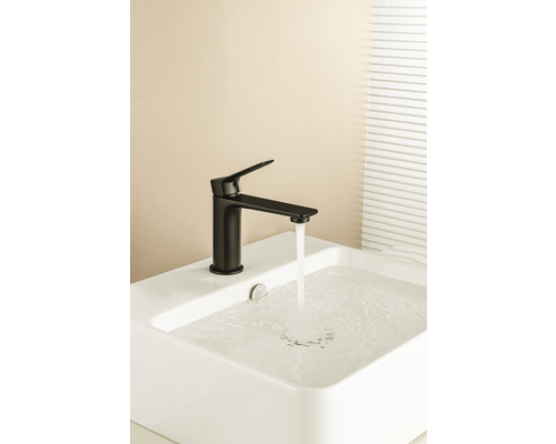 Baterie neagră pe o chiuvetă albă cu apă curgătoare.