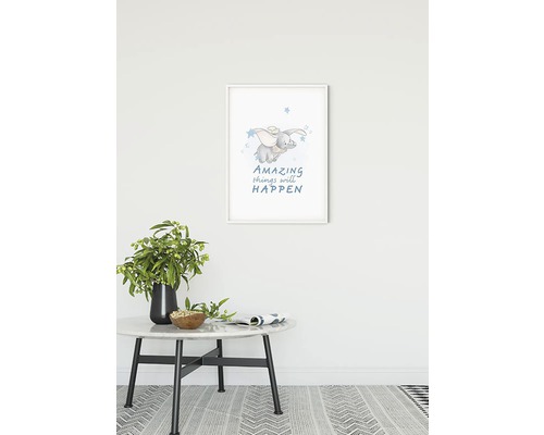 Artă de perete înrămată cu un motiv de elefant și textul ''Amazing things will happen'', plasată deasupra unei mese cu decor