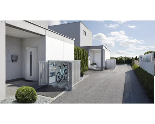 Cutie pentru biciclete în fața unei case cu uși deschise, în interior se află o bicicletă