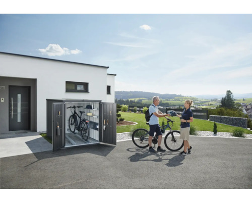 Cutie pentru biciclete în fața unei case cu două biciclete și două persoane