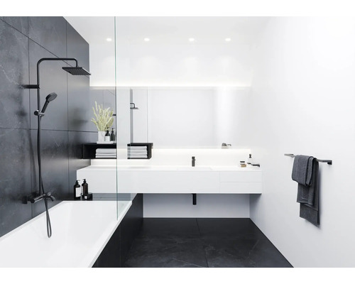 Baie modernă cu cadă, baterie de duș, chiuvetă și suport pentru prosop.