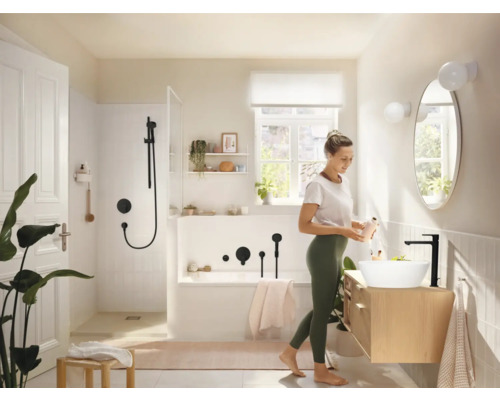 Baie luminoasă cu cadă, duș, chiuvetă și femeie