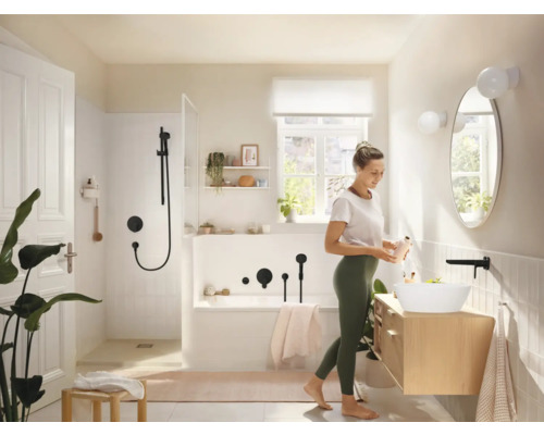 Baie luminoasă cu duș, cadă, chiuvetă și o femeie