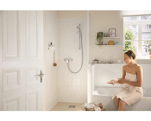 Baie luminoasă cu duș, cadă și o femeie cu prosop