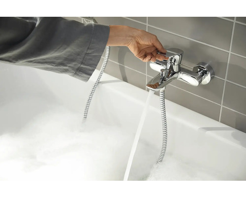 O mână acționează o baterie pe o cadă plină cu spumă