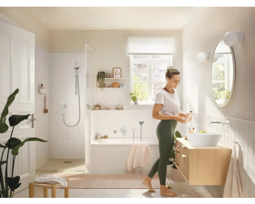 Baie luminoasă cu duș, cadă, lavoar și o femeie