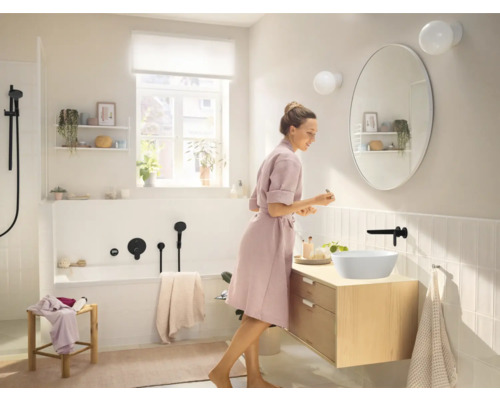 Baie luminoasă cu cadă, dulap de lavoar cu lavoar așezat și oglindă ovală