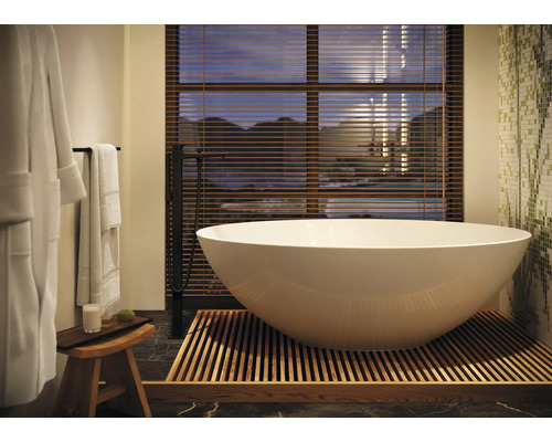 Cadă de baie independentă cu robinet și accesorii de baie într-o baie luminoasă.