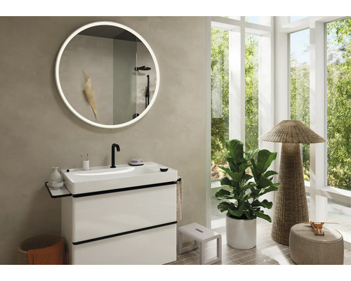 Baie modernă cu lavoar, oglindă rotundă cu iluminare și fereastră mare.