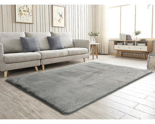 Cameră de zi cu covor gri, canapea, masă și comodă