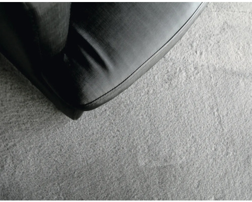 Prim-plan al unei canapele negre pe un covor gri.