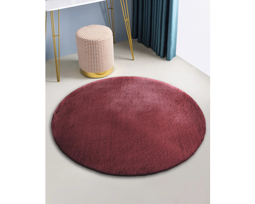 Covor rotund din imitație de blană într-o cameră cu taburet și masă