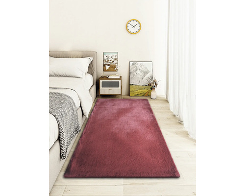 Covor dreptunghiular în fața unui pat într-un dormitor.