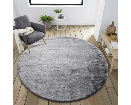 Covor rotund gri în sufragerie cu fotoliu și măsuță laterală.