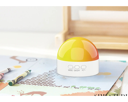 Lampă de noptieră cu abajur galben pe o masă cu creioane colorate și hârtie.