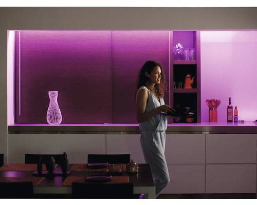 Bucătărie modernă cu rafturi și o femeie care poartă vase, iluminată cu iluminat decorativ