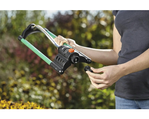 Femeie care montează un aspersor de gazon în grădină