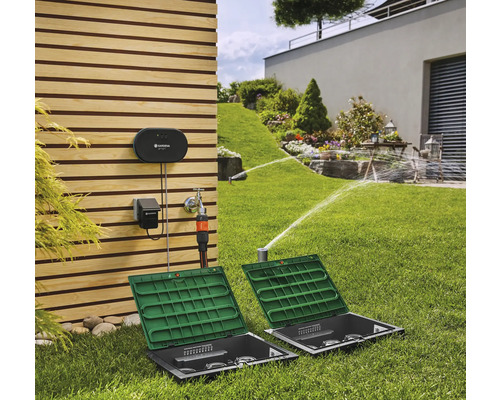 Sistem de irigare Gardena în grădină cu aspersoare de gazon și sistem de control pe peretele casei