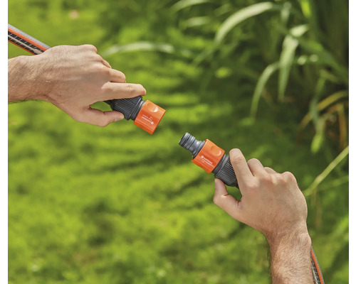 Două mâini conectează un cuplaj pentru furtun de grădină.