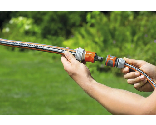 O persoană conectează două furtunuri de grădină cu un conector.