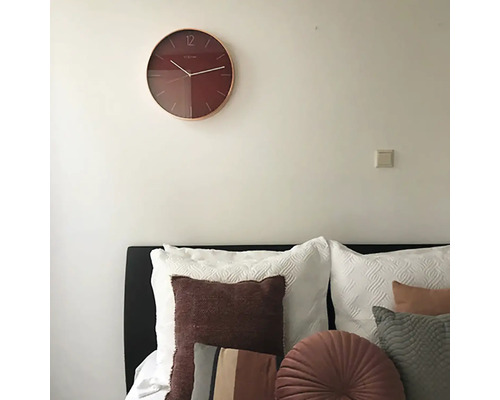 Ceas de perete deasupra unui pat cu perne