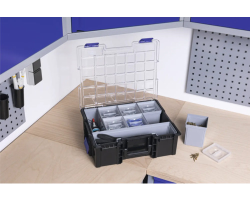 Cutie de scule deschisă cu capac transparent și compartimente pe un banc de lucru.