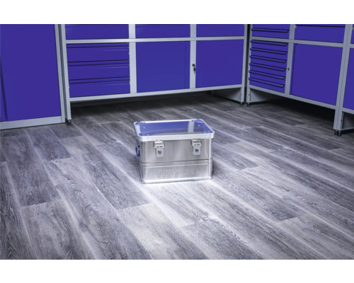 Cutie de scule din aluminiu pe podea în fața dulapurilor albastre de atelier