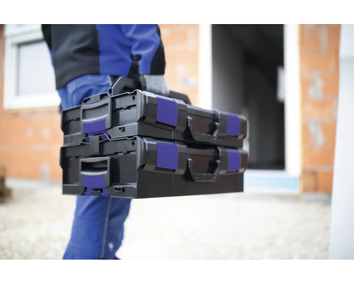 Artizan care transportă două cutii de scule negre la locul de utilizare