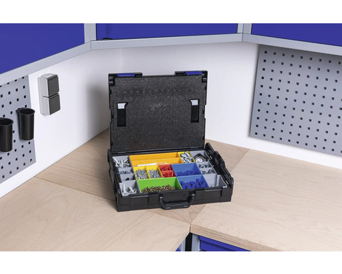 Cutie de sortiment deschisă cu diverse șuruburi și piese mici pe un banc de lucru