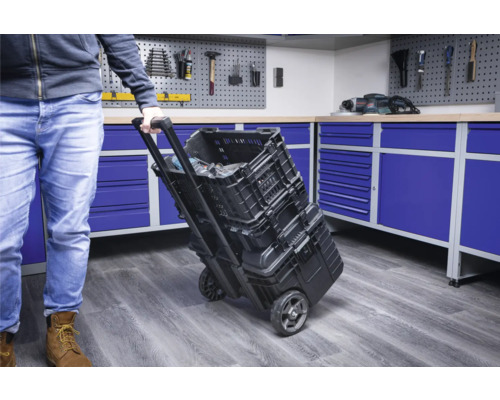 O persoană trage un cărucior cu cutie de scule cu cutii de scule într-un atelier.