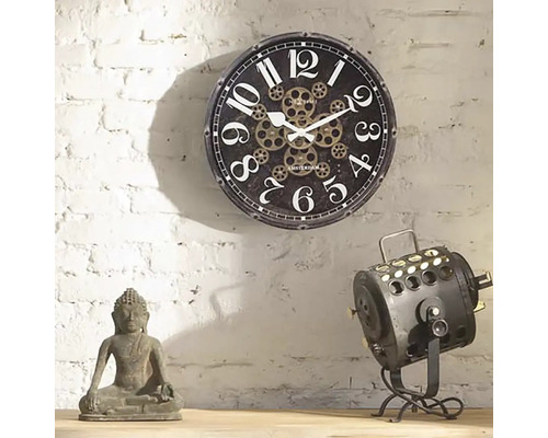 Scenă decorativă cu un ceas de perete cu model de roată dințată, o statuie a lui Buddha și o lampă de reflector.