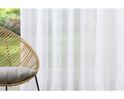 Cameră luminoasă cu perdea albă și fotoliu din ratan