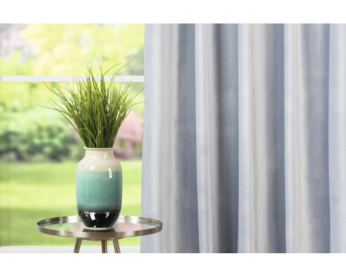 Cameră decorativă cu perdea albastră, masă și vază cu plantă verde.