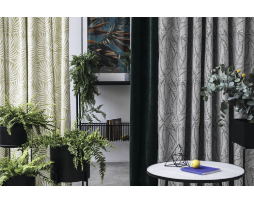 Vedere a camerei cu perdele cu model de frunze, plante de interior și măsuță laterală