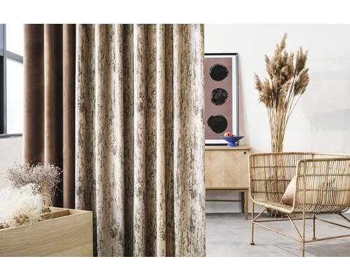 Living decorativ cu perdele cu model, dulap din lemn și fotoliu din ratan.