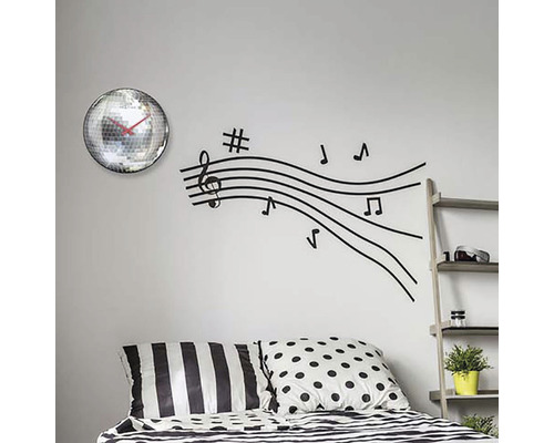 Decor de perete cu ceas cu bilă disco și autocolant de perete cu linii de note muzicale deasupra unui pat.