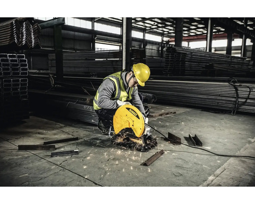 Un bărbat taie metal cu un ferăstrău circular pentru metal într-o hală de fabrică.