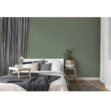 Dormitor cu pat, noptieră și decorațiuni în fața unui perete verde