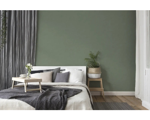 Dormitor cu pat, noptieră și decorațiuni în fața unui perete verde