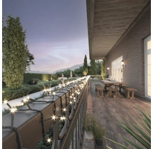 Terasa cu șir de lumini pe o balustradă cu grădină în fundal.