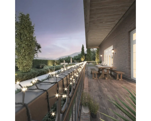 Terasa cu șir de lumini pe o balustradă cu grădină în fundal.