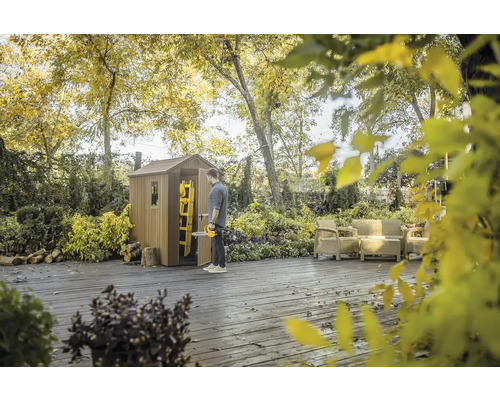 Scenă cu o căsuță de grădină din lemn, o persoană cu un tăietor de gard viu, o scară și mobilier de grădină pe o terasă