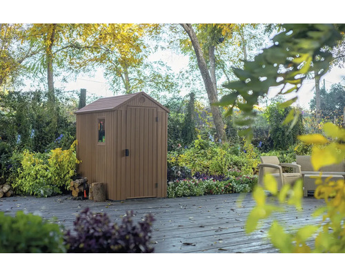 Magazie de grădină din plastic cu fereastră și ușă pe o terasă din grădină.